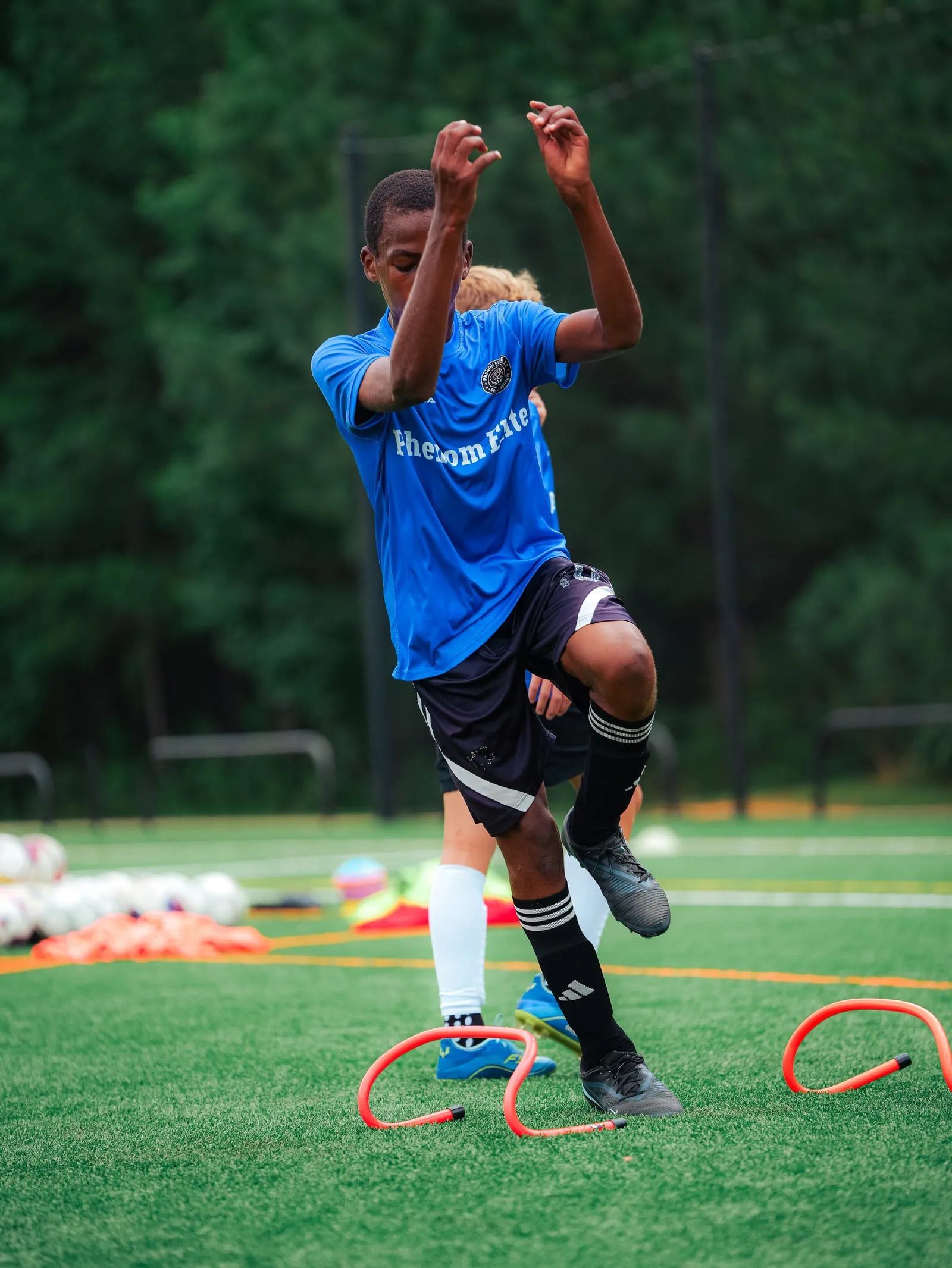 A player stepping through a set of low hurdles in a footwork drill